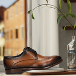 Men's Bugatti derby cognac leather shoes with a round toe and wing tip featuring a stacked heel , a leather outsole , and laces fastening.