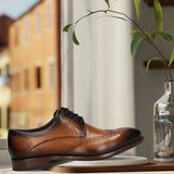 Men's Bugatti derby cognac leather shoes with a round toe and wing tip featuring a stacked heel , a leather outsole , and laces fastening.