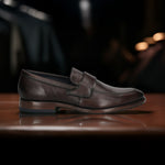 A brown Men's bugatti Penny Loafer featuring a round toe apron toe, stacked heel. Made from premium genuine leather with a durable leather outsole, this slip-on design offers both style and comfort.