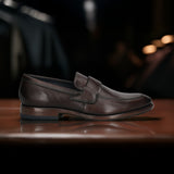 A brown Men's bugatti Penny Loafer featuring a round toe apron toe, stacked heel. Made from premium genuine leather with a durable leather outsole, this slip-on design offers both style and comfort.