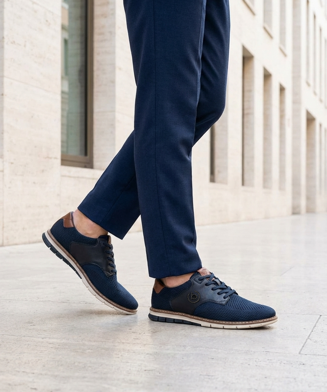 Lifestyle image of bugatti Sandman Comfort Casual Shoes in dark blue, paired with tailored blue trousers.