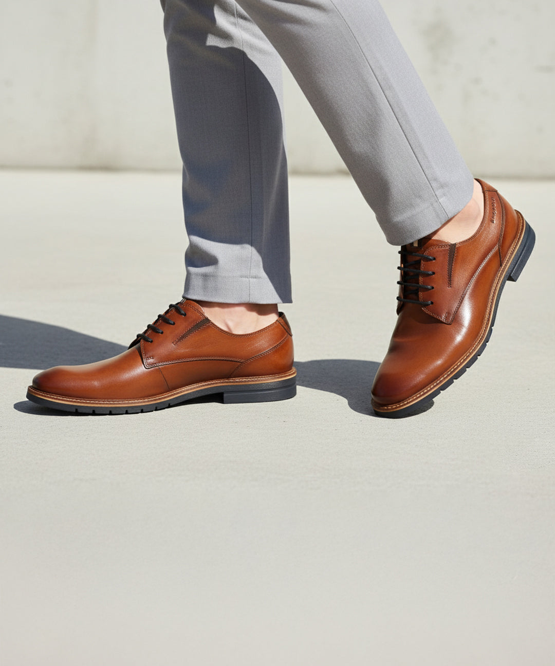 bugatti Merlo cognac leather dress shoes with black laces, paired with gray dress pants.
