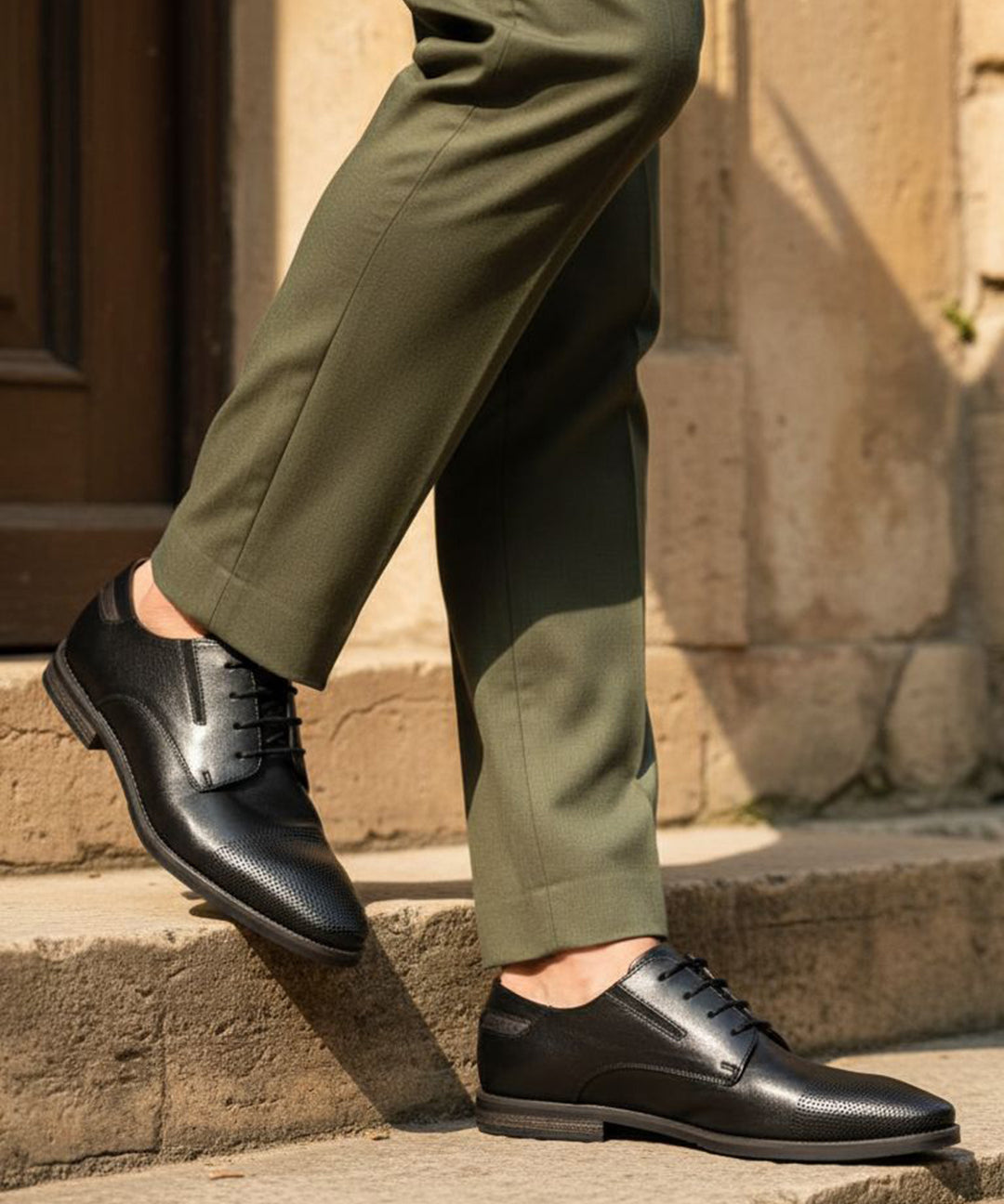 bugatti Menello black leather formal shoes with a textured finish, shown on a person with green dress pants.
