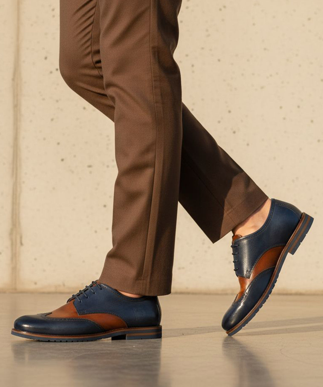 bugatti Caleo Exko dark blue leather formal shoe with brown accents, paired with brown trousers in a lifestyle shot.
