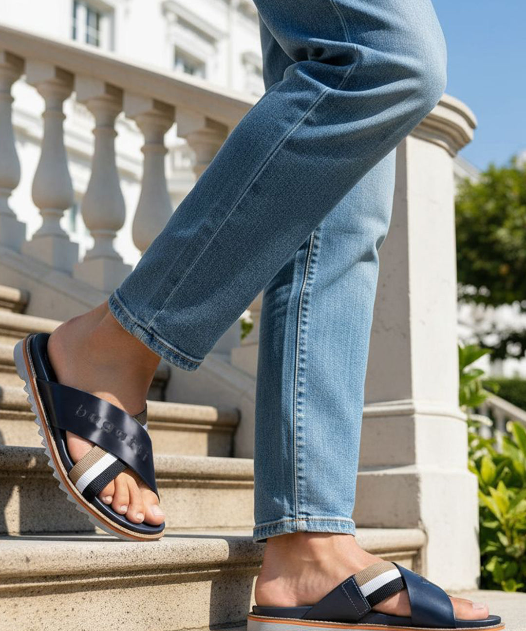 bugatti Limon dark blue leather sandals with cross straps, worn with jeans on stairs.
