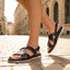 bugatti Limon dark blue leather sandals with criss-cross straps and a back strap on a cobblestone street.

