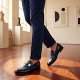 bugatti Mansueto Flex Blue premium leather penny loafers with a silver buckle, worn with navy slacks.