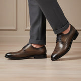bugatti Livorno Flex Evo dark grey leather formal shoes, with brogue detailing, styled with grey trousers.
