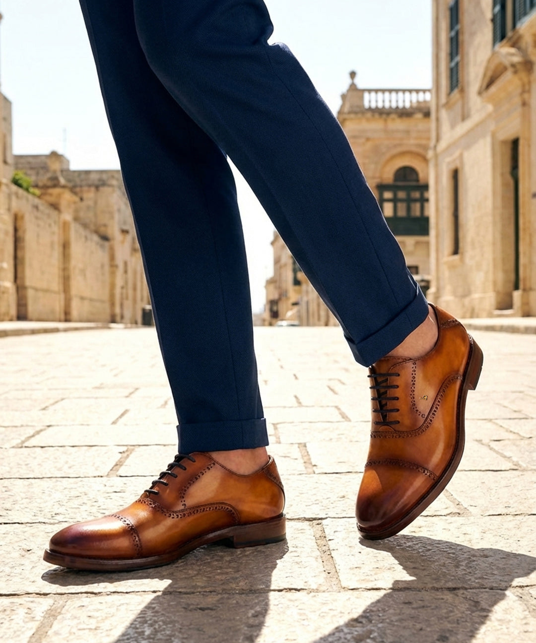 bugatti Liverta yellow leather oxford shoes with dark laces and decorative stitching worn with dark blue pants.
