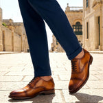 bugatti Liverta yellow leather oxford shoes with dark laces and decorative stitching worn with dark blue pants.
