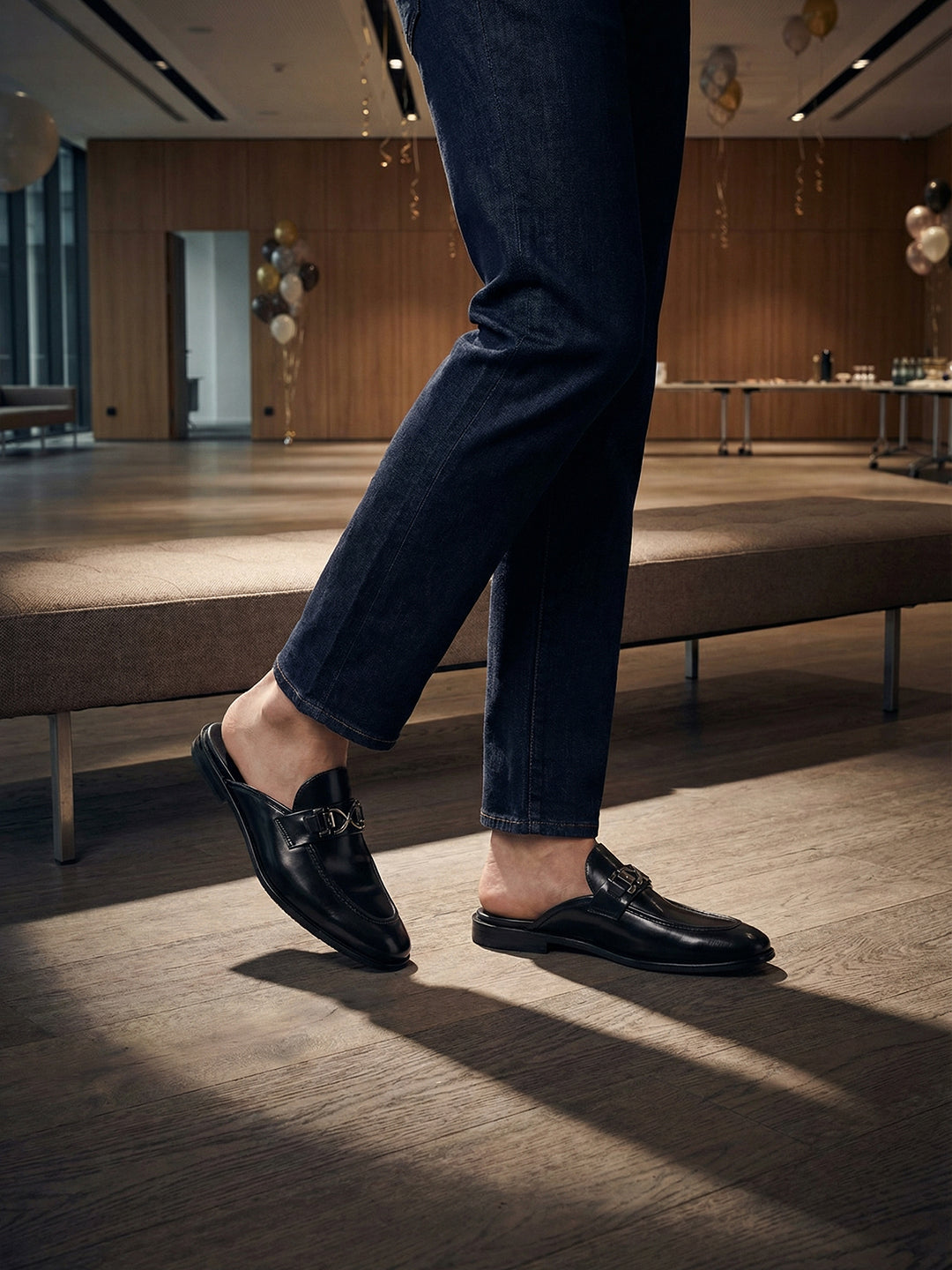Lifestyle shot of bugatti Rico Black leather slip-on shoes, featuring a metal buckle detail.
