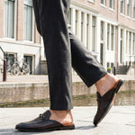 Lifestyle shot of bugatti Rico Brown premium leather slip-on shoe, featuring a woven texture and a metal horse-bit detail.
