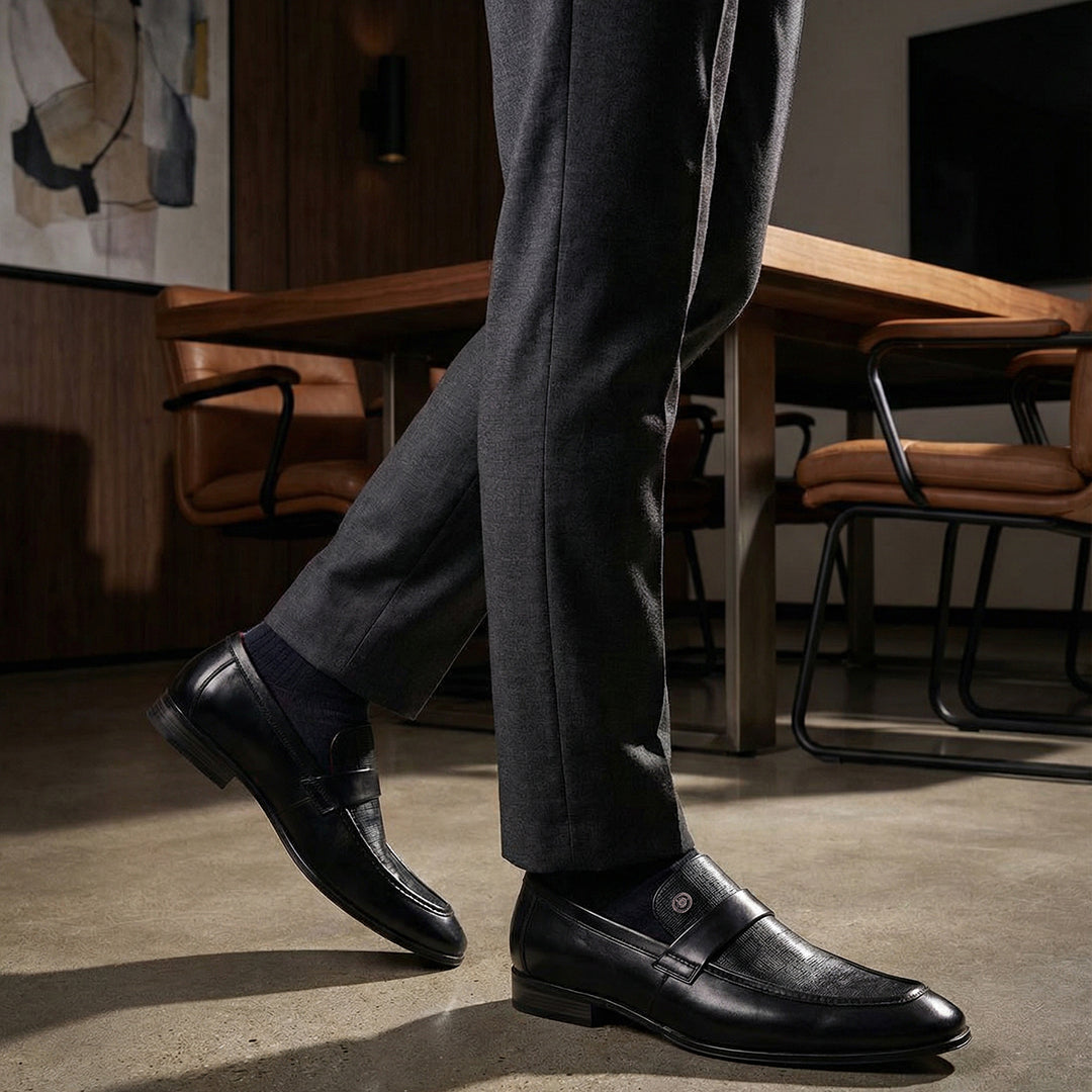 bugatti Matina black premium leather penny loafers with subtle texture, paired with dark gray dress pants and dress socks.