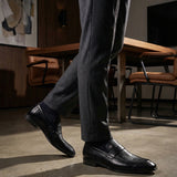 bugatti Matina black premium leather penny loafers with subtle texture, paired with dark gray dress pants and dress socks.