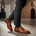 Lifestyle view of bugatti Matina yellow premium leather penny loafers with brown socks and grey slacks.
