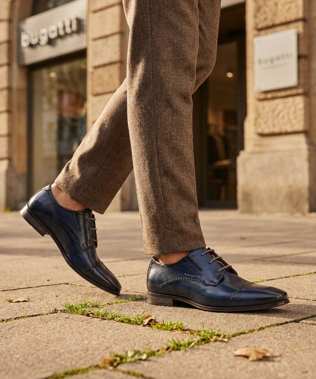 Lifestyle shot of bugatti Margo blue leather derby shoes with brown laces and textured upper, paired with brown tweed trousers.
