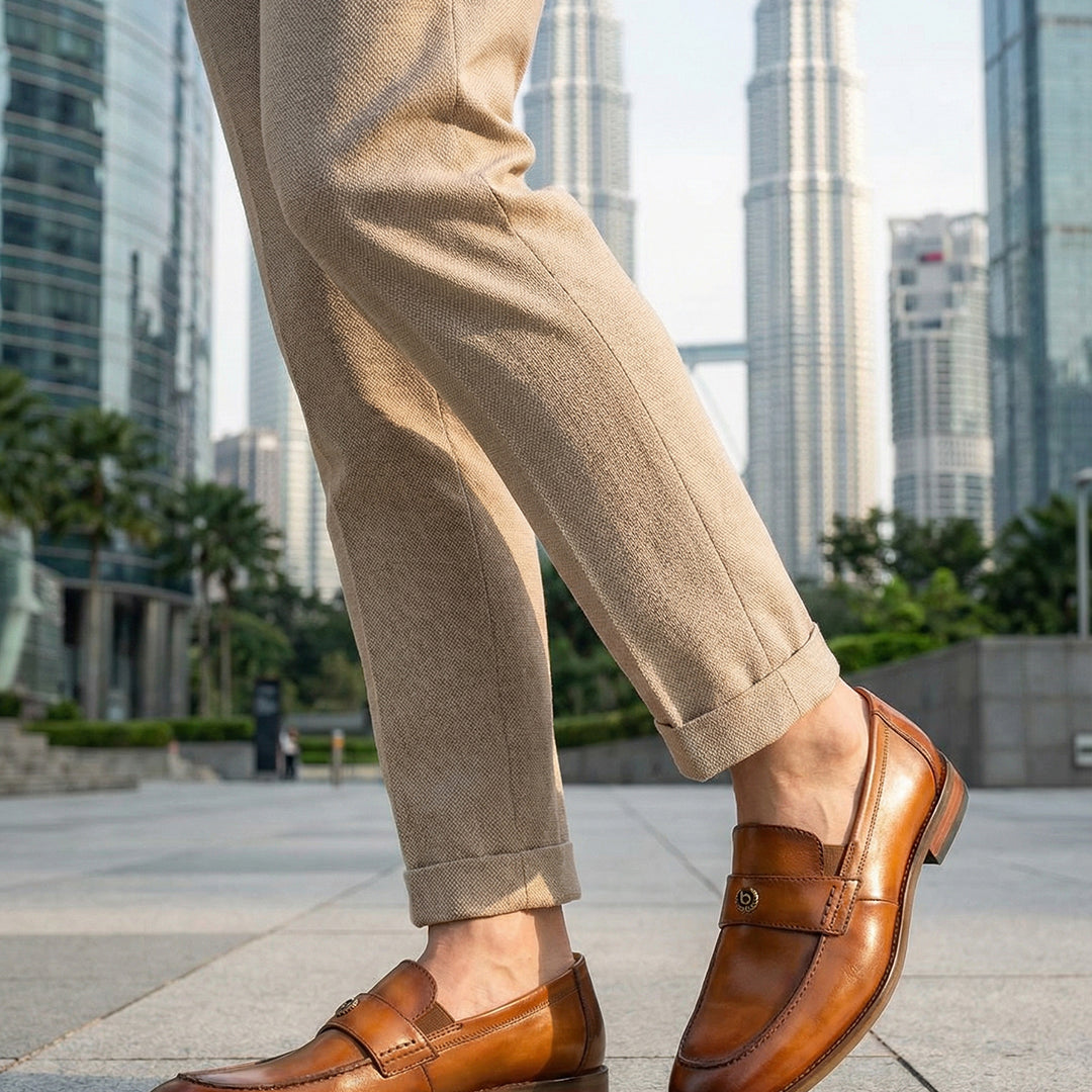 bugatti Sula Revo Yellow premium leather penny loafers, shown with khaki pants on a cityscape background.
