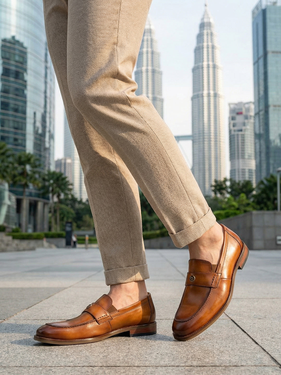 bugatti Sula Revo Yellow premium leather penny loafers, shown with khaki pants on a cityscape background.
