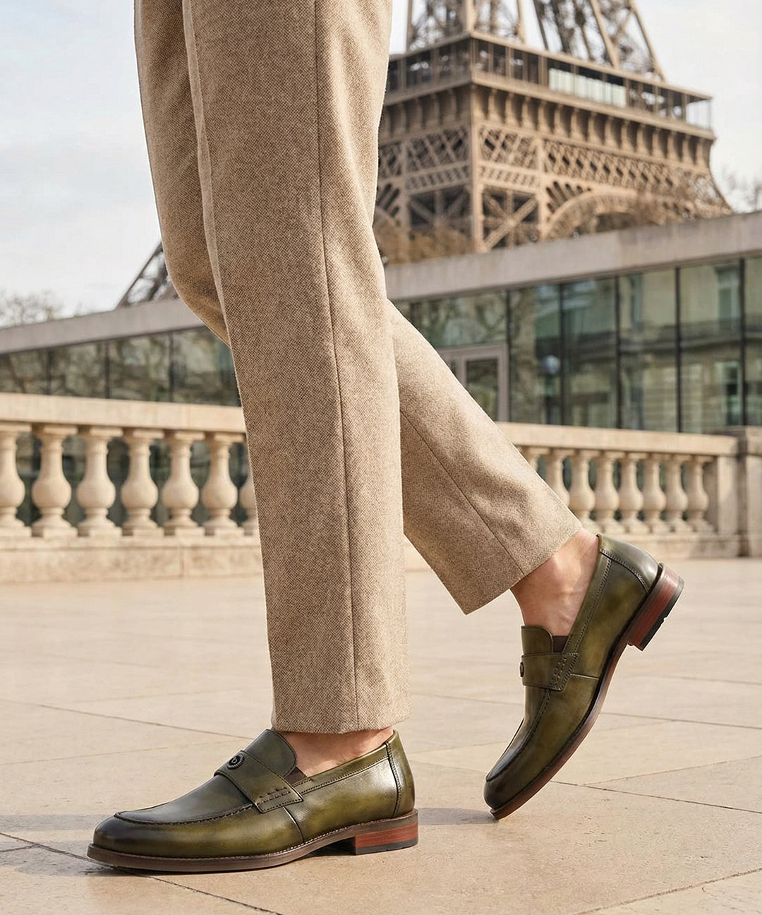 bugatti Sula Revo Green premium leather penny loafers, worn with tan trousers, with the Eiffel Tower in the background.