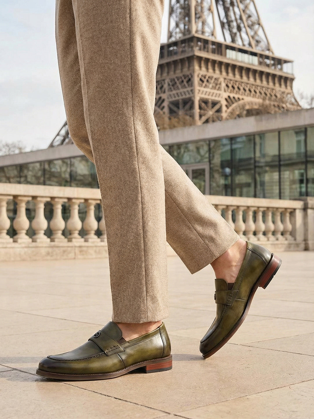 bugatti Sula Revo Green premium leather penny loafers, worn with tan trousers, with the Eiffel Tower in the background.