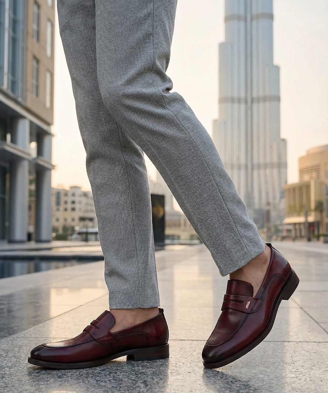bugatti Sula Revo red leather loafers with a penny strap detail, styled with grey dress pants.
