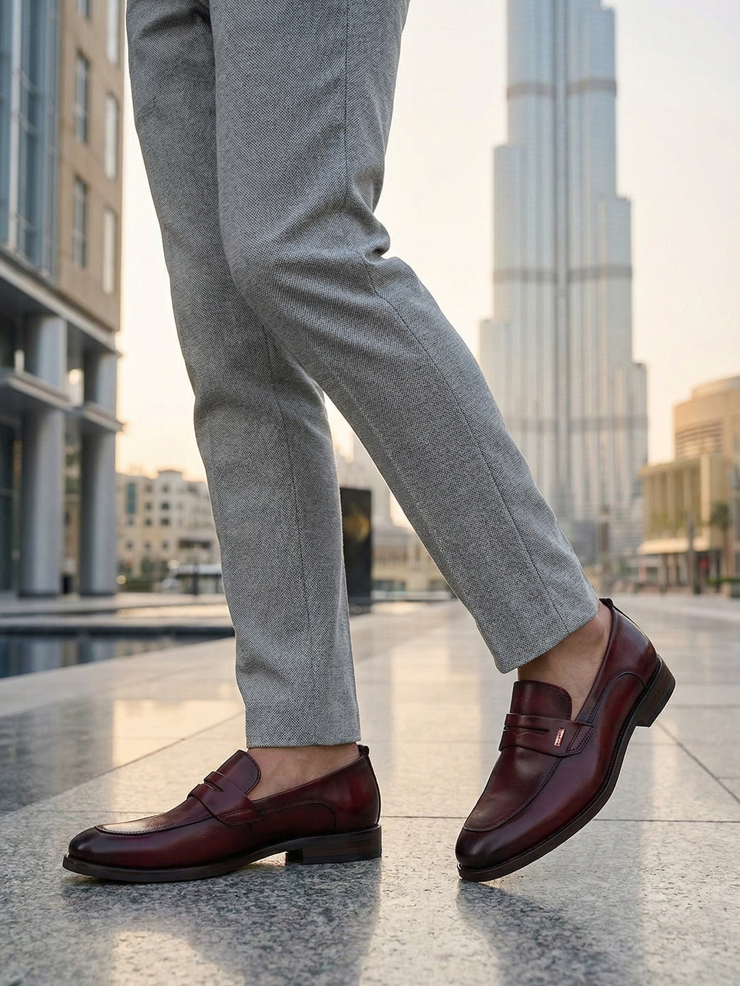 bugatti Sula Revo red leather loafers with a penny strap detail, styled with grey dress pants.
