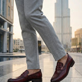 bugatti Sula Revo red leather loafers with a penny strap detail, styled with grey dress pants.
