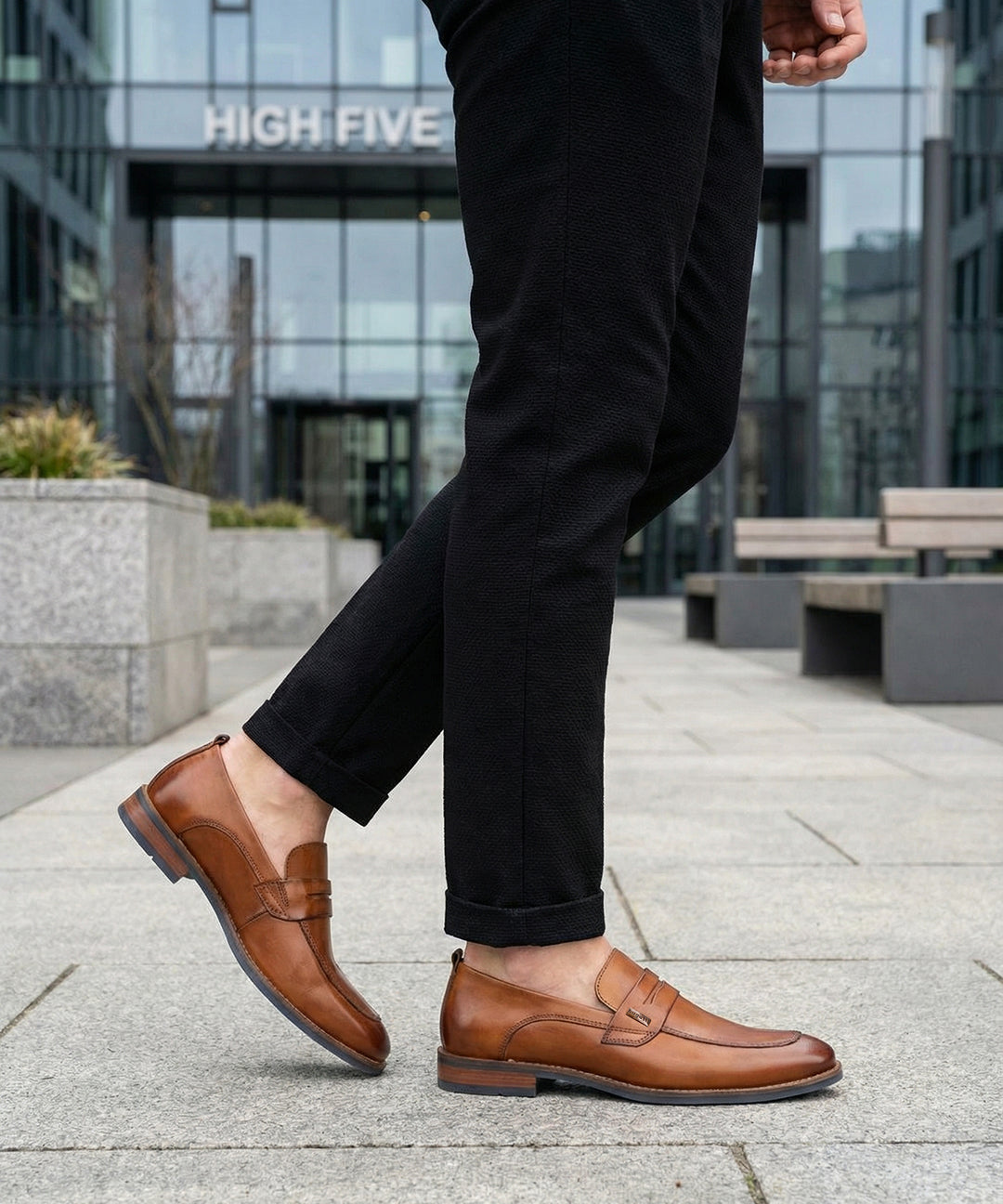 bugatti Sula Revo cognac penny loafers in premium leather, paired with black textured pants, outdoor setting.
