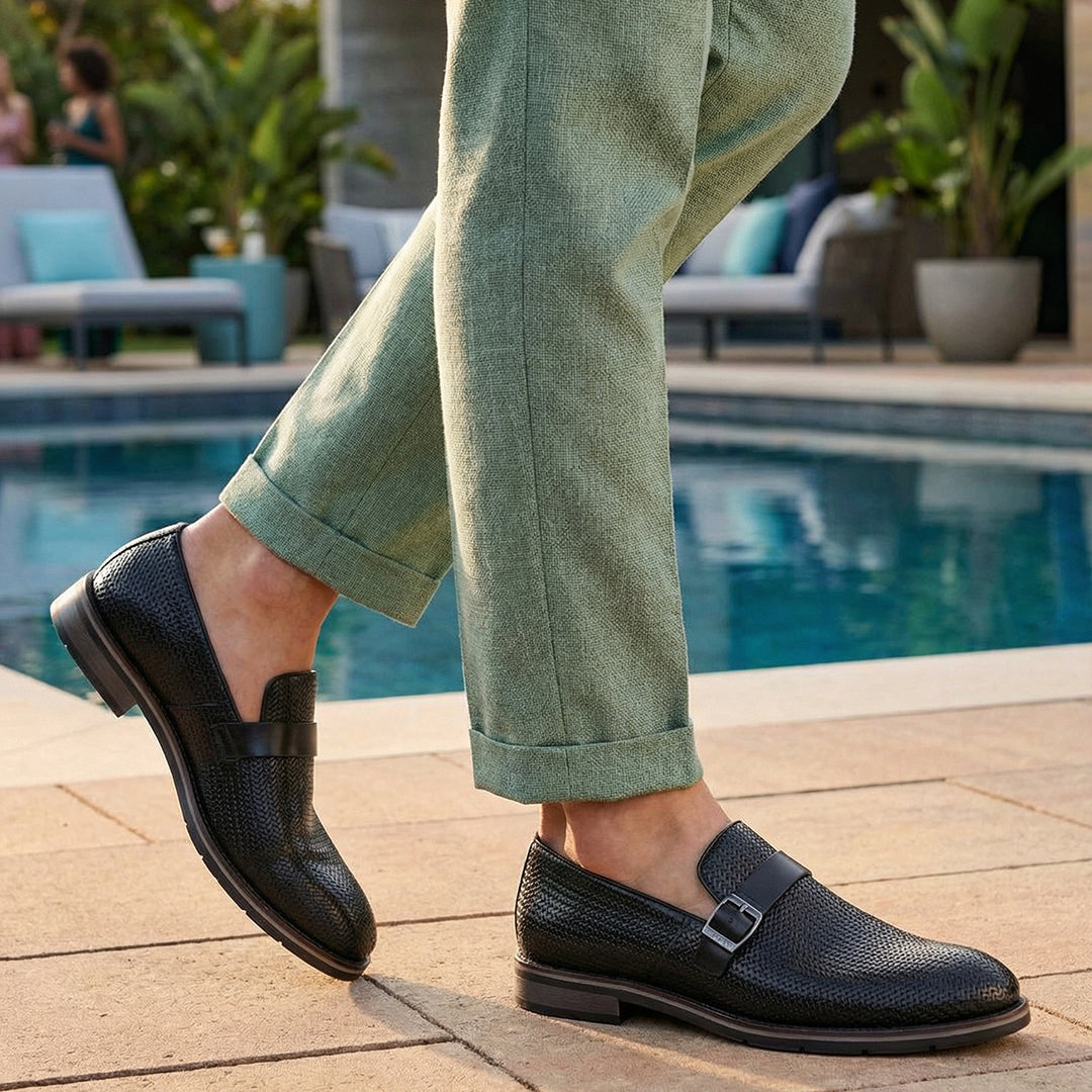 bugatti Laziano black leather loafers with a buckle, worn with green pants near a pool.
