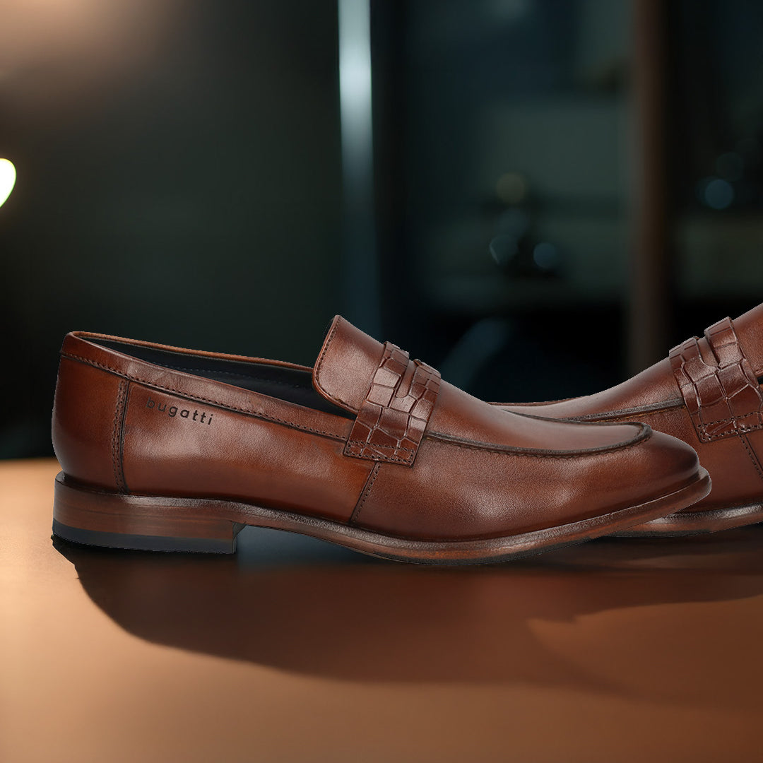 A cognac Men's bugatti Penny Loafer featuring a round toe apron toe, stacked heel. Made from premium genuine leather with a durable leather outsole, this slip-on design offers both style and comfort.