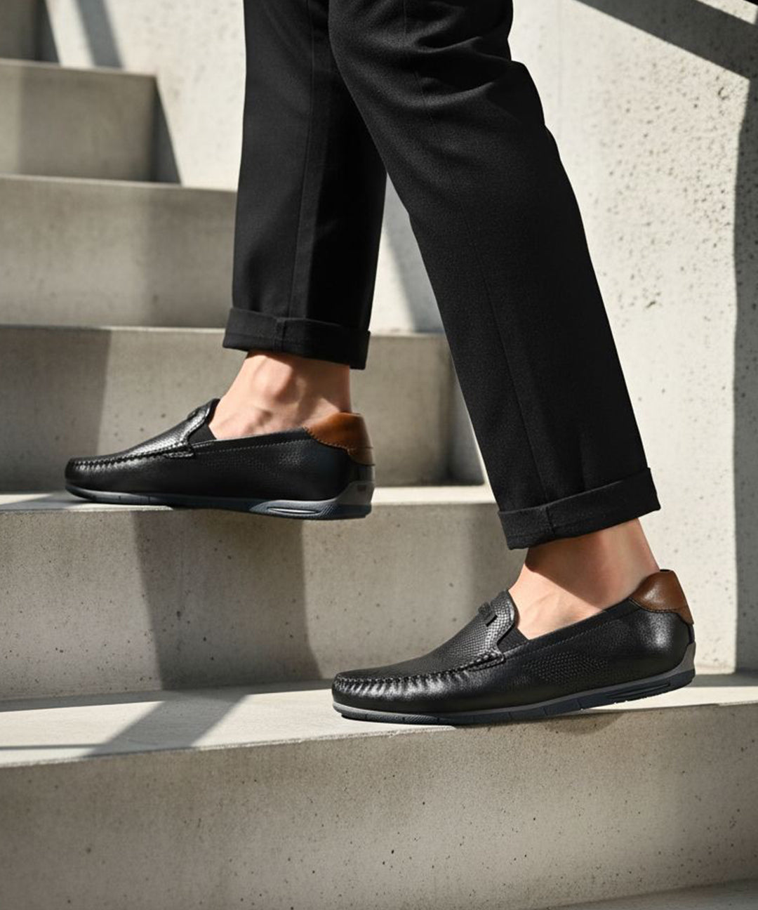 bugatti Chesley dark blue leather slip-on shoe with brown accent on a person walking on stairs.