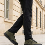 Lifestyle shot of bugatti Columb Dark Green Comfort Sneakers, worn with dark gray pants and olive green coat.