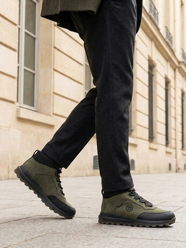 Lifestyle shot of bugatti Columb Dark Green Comfort Sneakers, worn with dark gray pants and olive green coat.