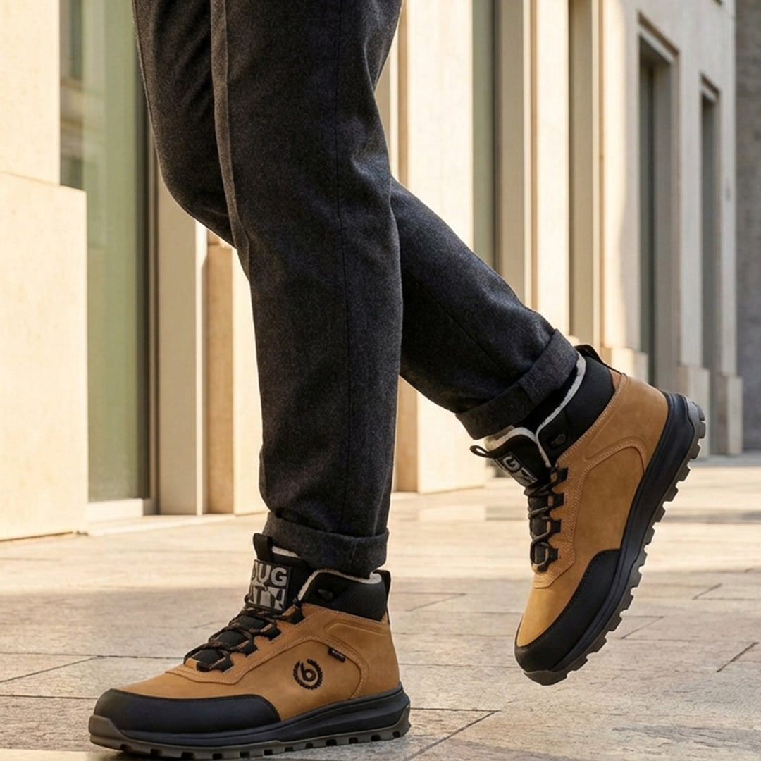 Lifestyle view of bugatti Columb Cognac Comfort Sneakers, with dark trousers and light-colored building in the background.