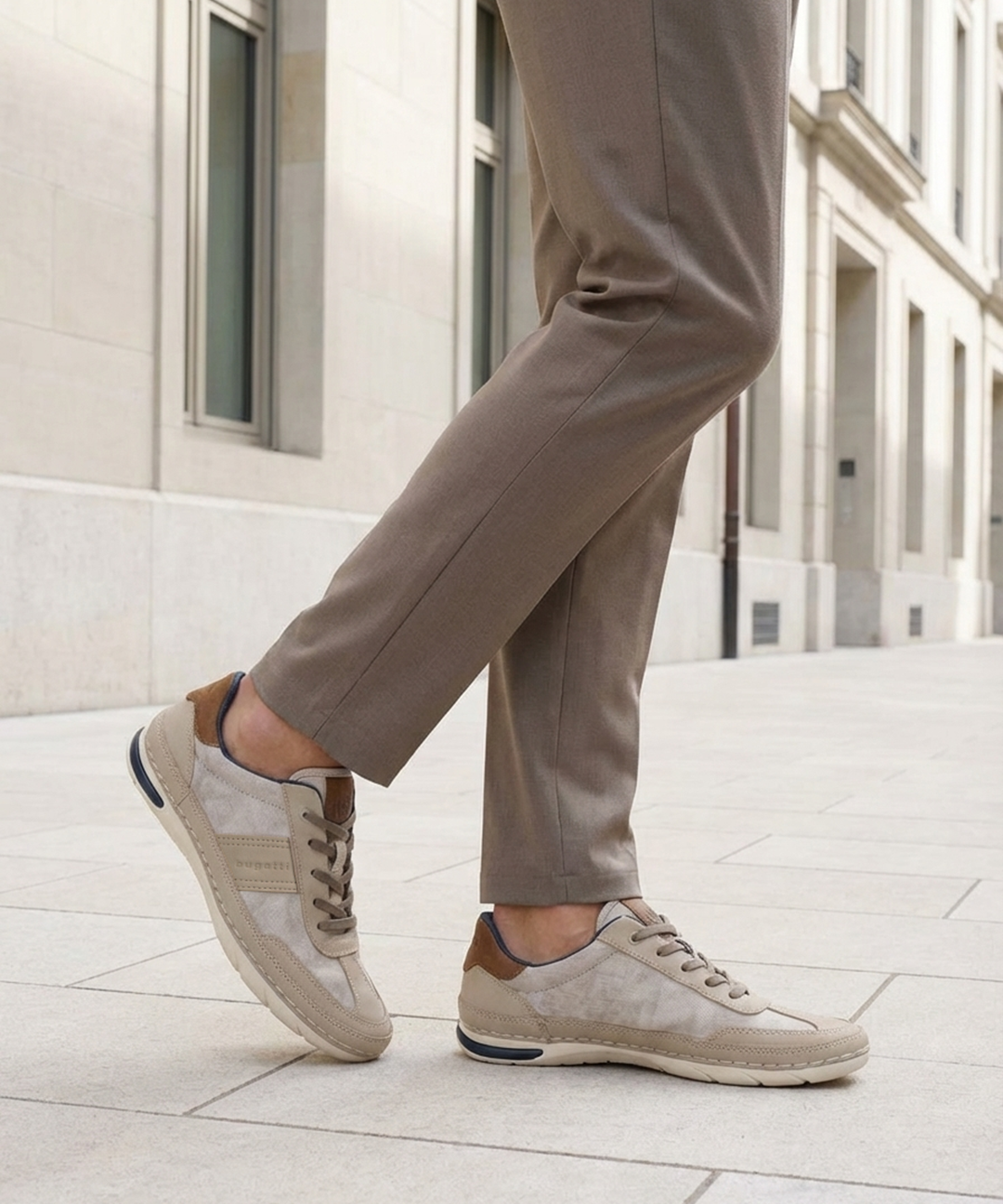 Lifestyle shot of bugatti Glenans sand comfort sneakers, with brown accent, worn with brown trousers.
