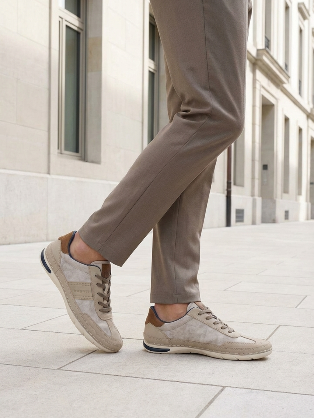 Lifestyle shot of bugatti Glenans sand comfort sneakers, with brown accent, worn with brown trousers.
