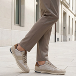 Lifestyle shot of bugatti Glenans sand comfort sneakers, with brown accent, worn with brown trousers.
