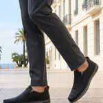 Lifestyle shot of bugatti Glenans black Comfort Slip-Ons casual shoes, paired with gray dress pants.