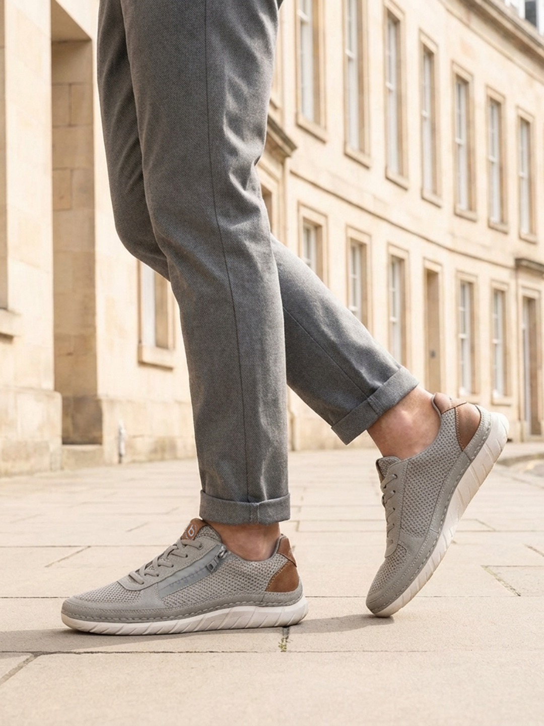 Lifestyle view of bugatti Compton grey comfort sneakers with mesh fabric, leather trim, zipper detail, and white soles.
