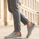 Lifestyle view of bugatti Compton grey comfort sneakers with mesh fabric, leather trim, zipper detail, and white soles.
