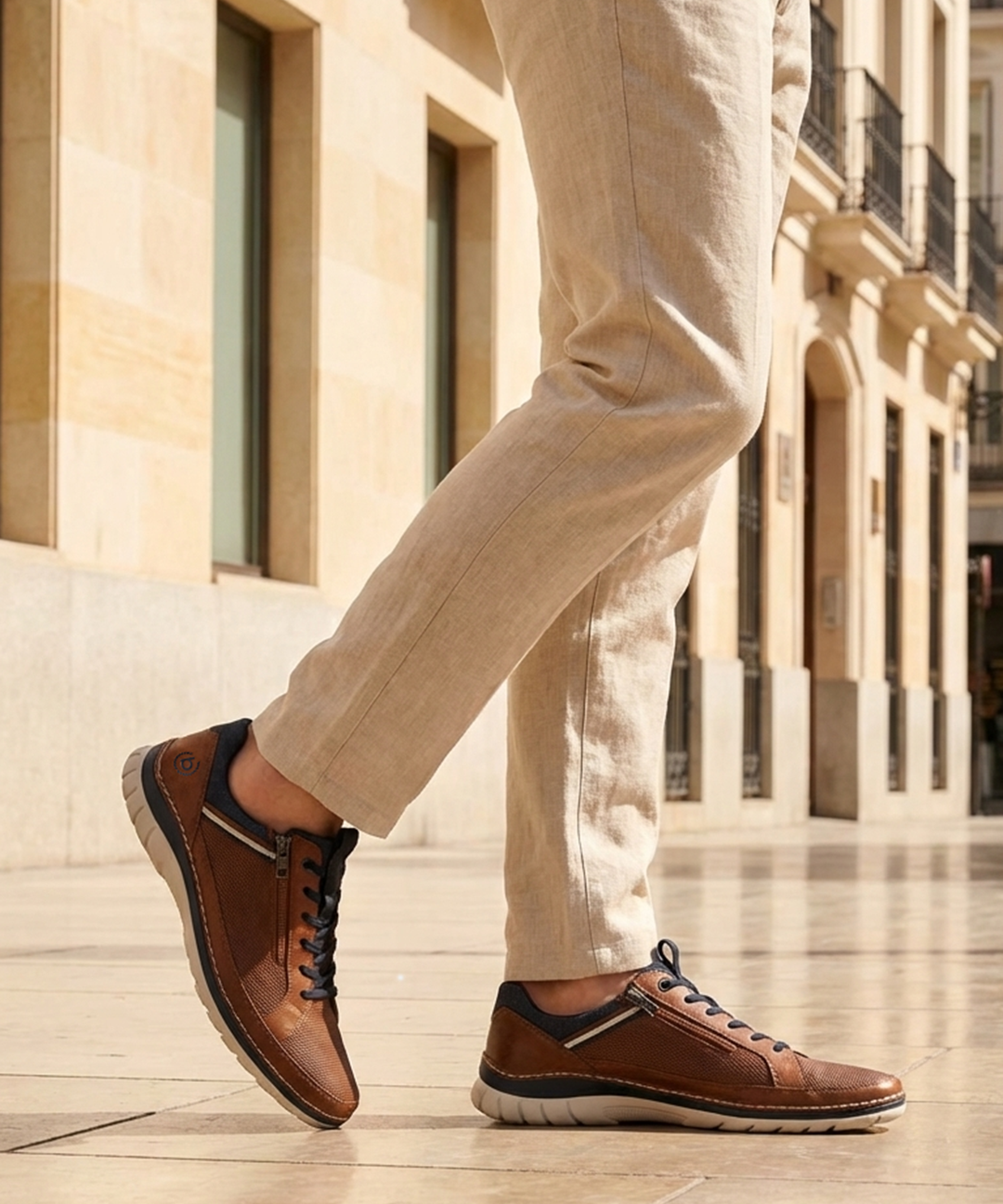 Bugatti Rickson cognac comfort sneakers, side view. Brown textured leather shoes with laces and side zipper, worn with tan pants.
