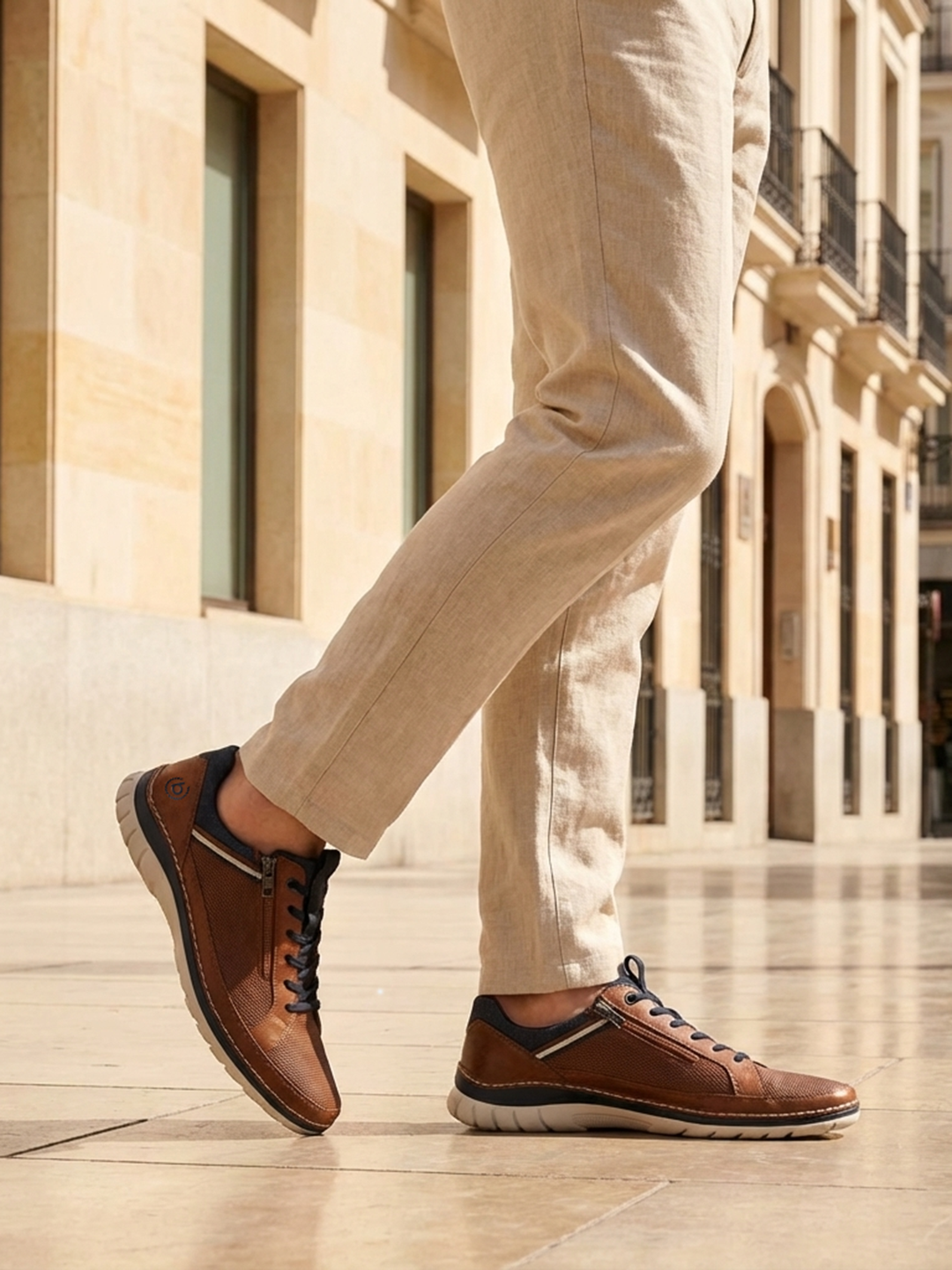 Bugatti Rickson cognac comfort sneakers, side view. Brown textured leather shoes with laces and side zipper, worn with tan pants.
