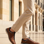 Bugatti Rickson cognac comfort sneakers, side view. Brown textured leather shoes with laces and side zipper, worn with tan pants.

