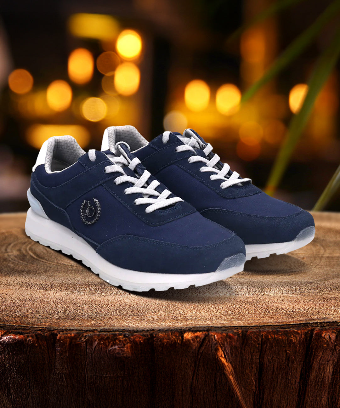 bugatti Atus dark blue sneakers with white laces and soles on a wooden surface with a blurred background.
