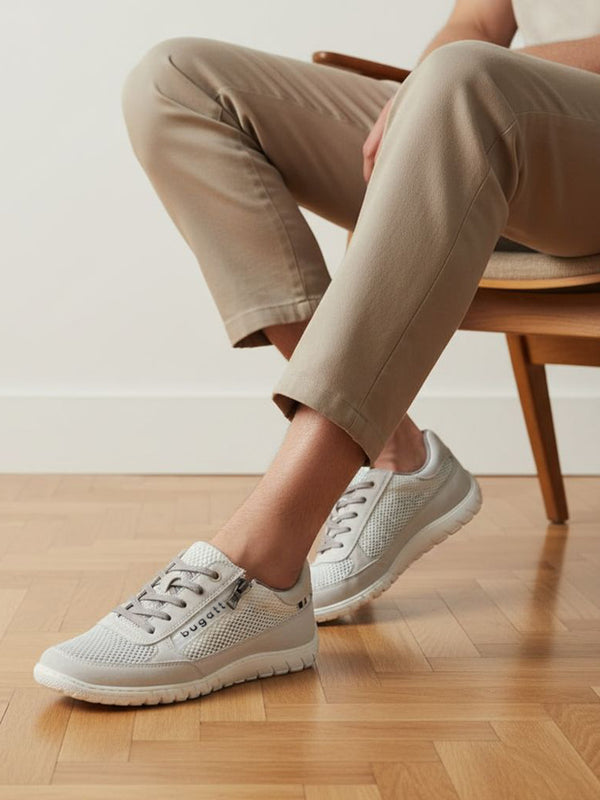 Lifestyle image of bugatti white sneakers, shown with a mesh texture, zipper accent, and worn with casual trousers.