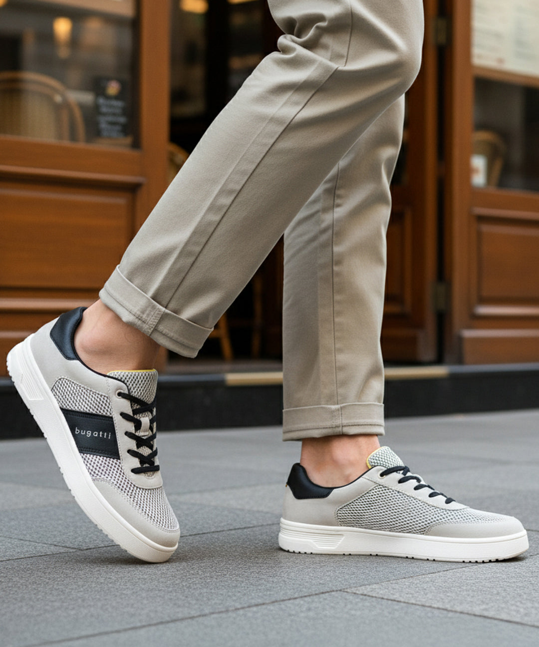 Lifestyle shot of bugatti Mackay light grey comfort sneakers with a black accent and white sole.
