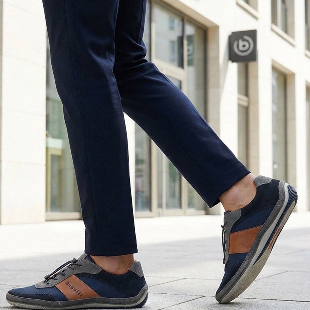 Lifestyle shot of a person wearing navy trousers and bugatti Canario Grey sneakers with brown leather accents.