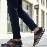Lifestyle shot of a person wearing navy trousers and bugatti Canario Grey sneakers with brown leather accents.