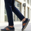 Lifestyle shot of a person wearing navy trousers and bugatti Canario Grey sneakers with brown leather accents.