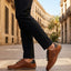Lifestyle shot of bugatti Canario Cognac Premium Leather Comfort Sneakers worn with black trousers on a city street.